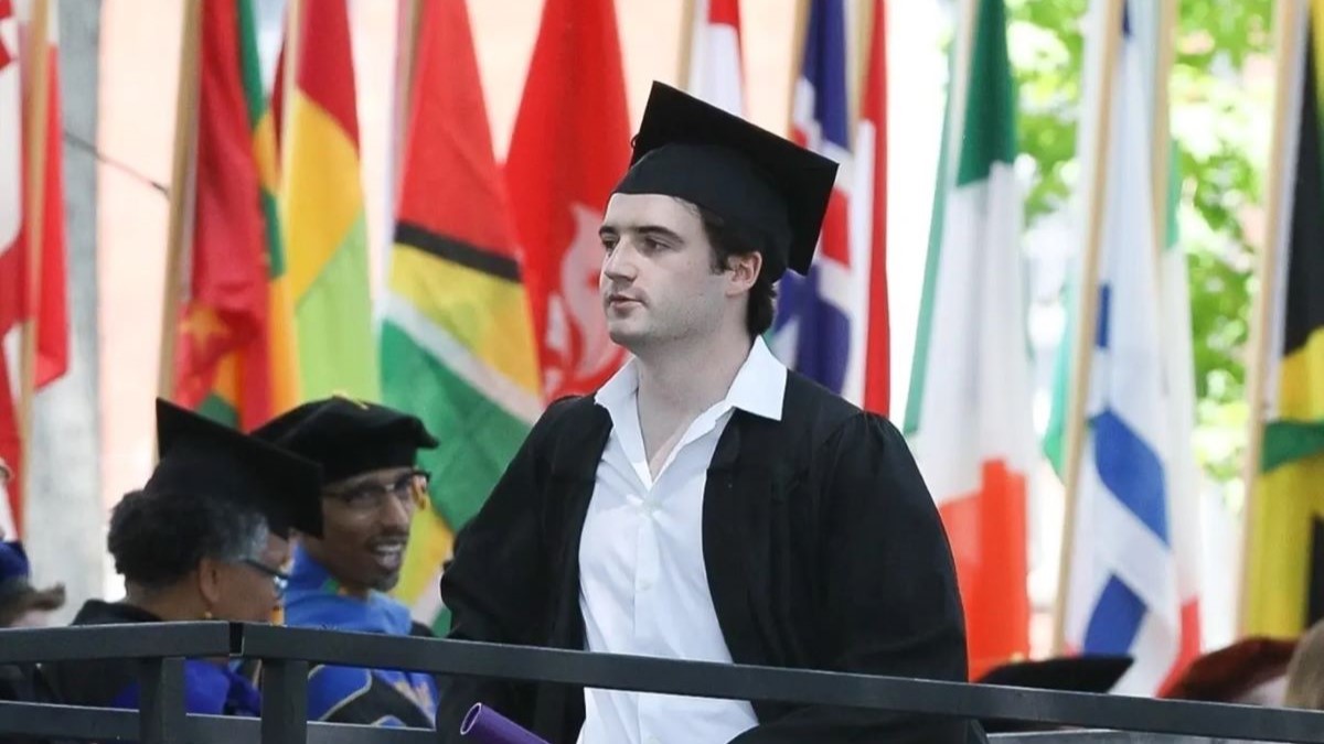 Liam Flockhart wearing graduation cap and gown and walking in crowd