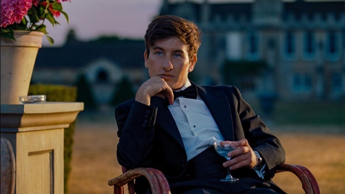 Barry Keoghan captured sitting in a chair holding a glass, wearing a tuxedo.
