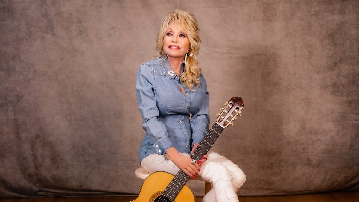 Dolly Parton is blue shirt with a guitar